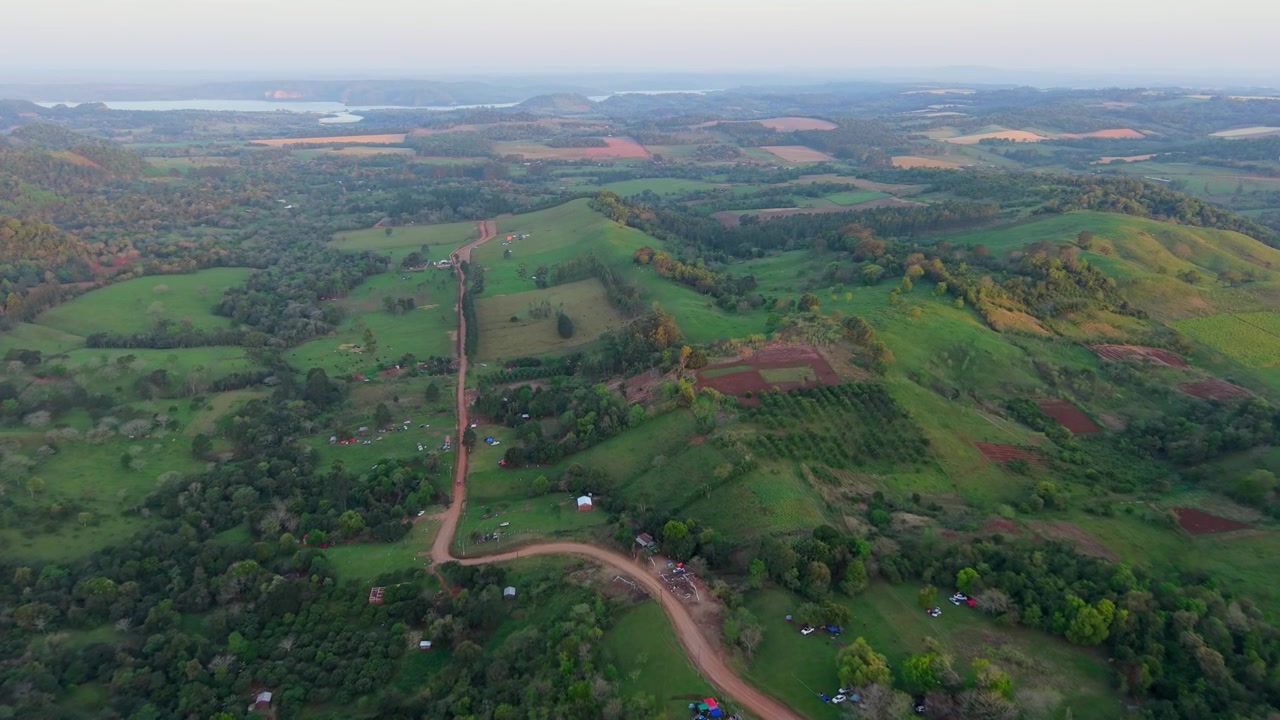 Sorvolando piste da rally in terra rossa, colline verdi e vegetazione circostante sotto il cielo del tardo pomeriggio prima del tramonto a Nueva Alborada, Paraguay