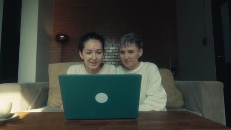 two women watching something funny on laptop