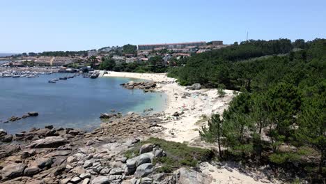 drone footage of marina beach with dark water and deep forest in spain