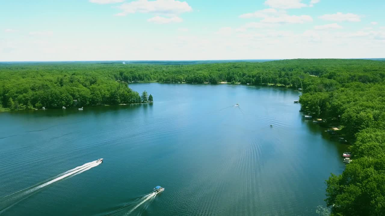 barcos de video aéreo de 4k en un lago rural hermoso, pintoresco y pequeño en michigan, estados unidos, en verano, agua azul cielo azul en un día soleado, todas las personas son irreconocibles