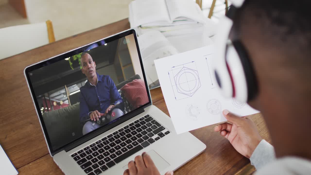 hombre de negocios afroamericano sentado en un escritorio usando una computadora portátil haciendo una videollamada con un colega masculino