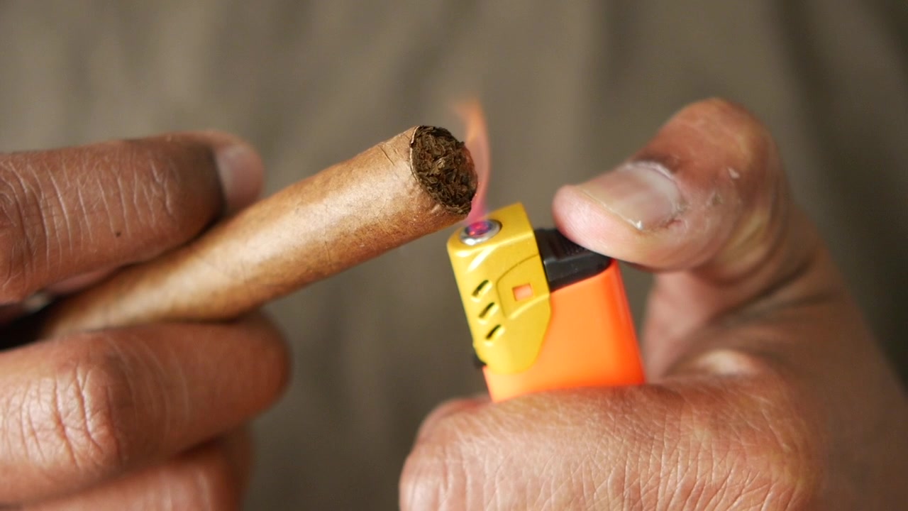 Primo piano di mani che accendono un sigaro con un accendino