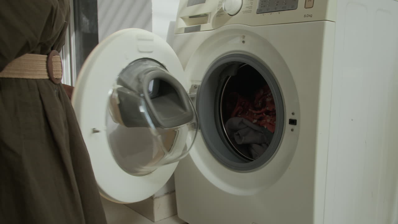 Anonymous Woman Setting Cycle of Loaded Washing Machine