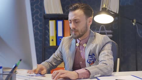 Charismatic-handsome-businessman-using-computer-in-office,-serious-and-focused.