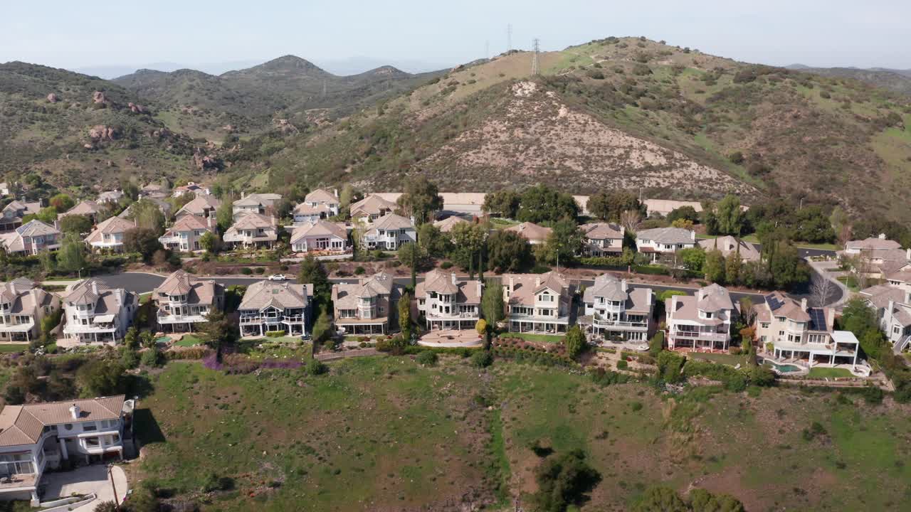 Aerial reverse pullback tilting up shot of upscale hillside homes in Lake Sherwood, California. 4K at 30 FPS