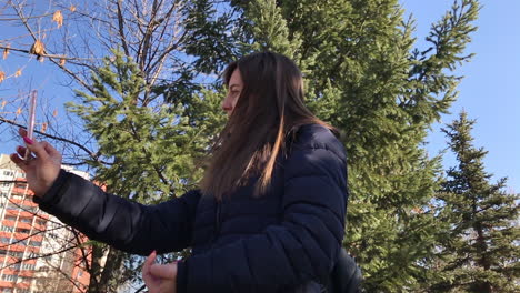 cámara lenta de una joven que se toma selfies con un smartphone usando una cámara frontal en un parque de la ciudad