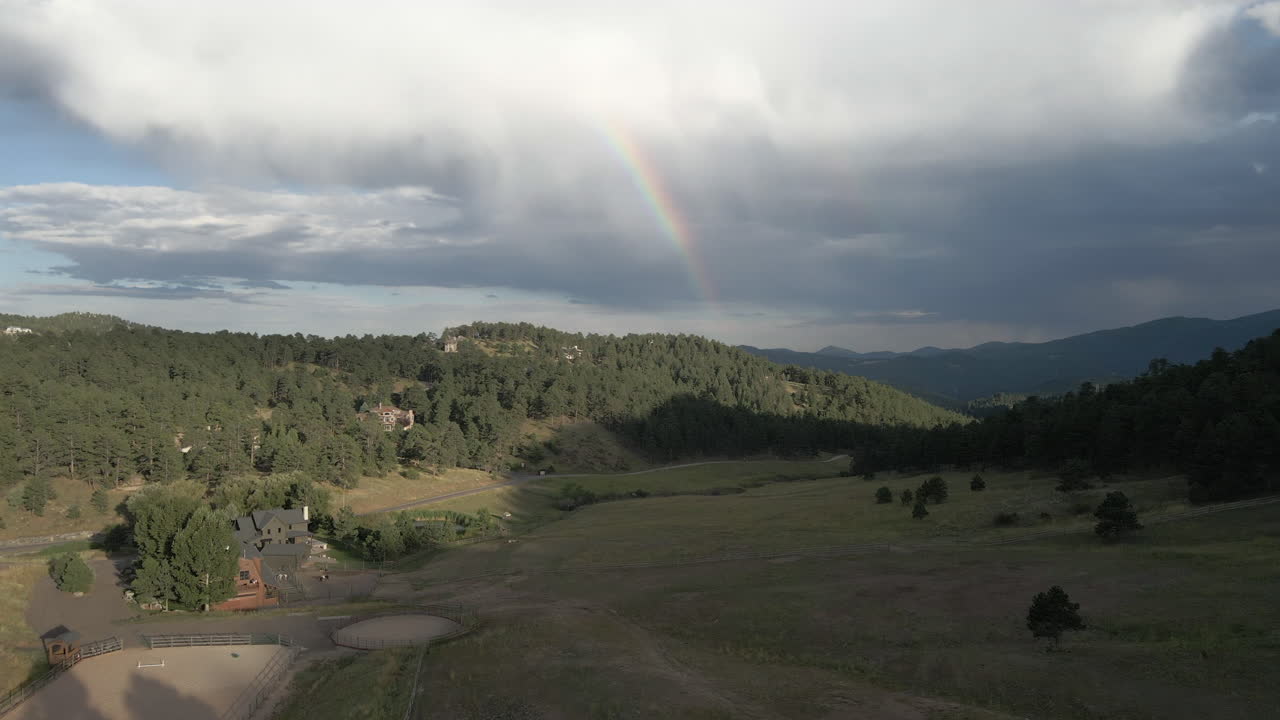 vuela sobre árboles y montañas con un arco iris en el fondo en colorado, estados unidos