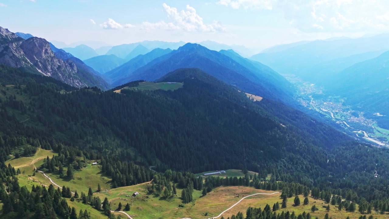 Stunning aerial footage flying over the dolomites, revealing the beautiful valley and doss del sabion peak under a clear summer sky