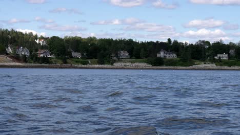 Classic-New-England-oceanfront-homes-viewed-from-water,-above-rocky-coastlines-in-slow-motino