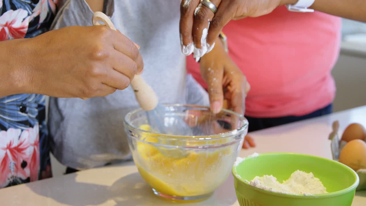 padre e hijo vertiendo harina en el cuenco y madre batiendo huevos 4k