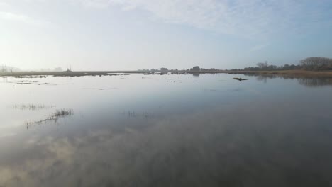 Drone-POV-of-a-mirror-lake-with-a-couple-of-Seagulls-flying-by