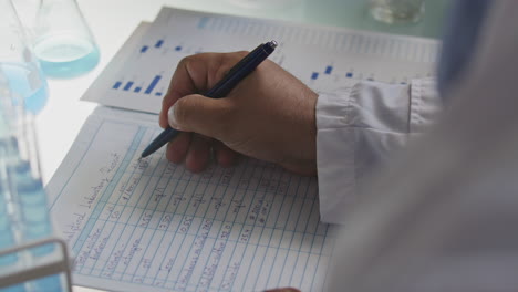hands of scientist taking notes on laboratory report