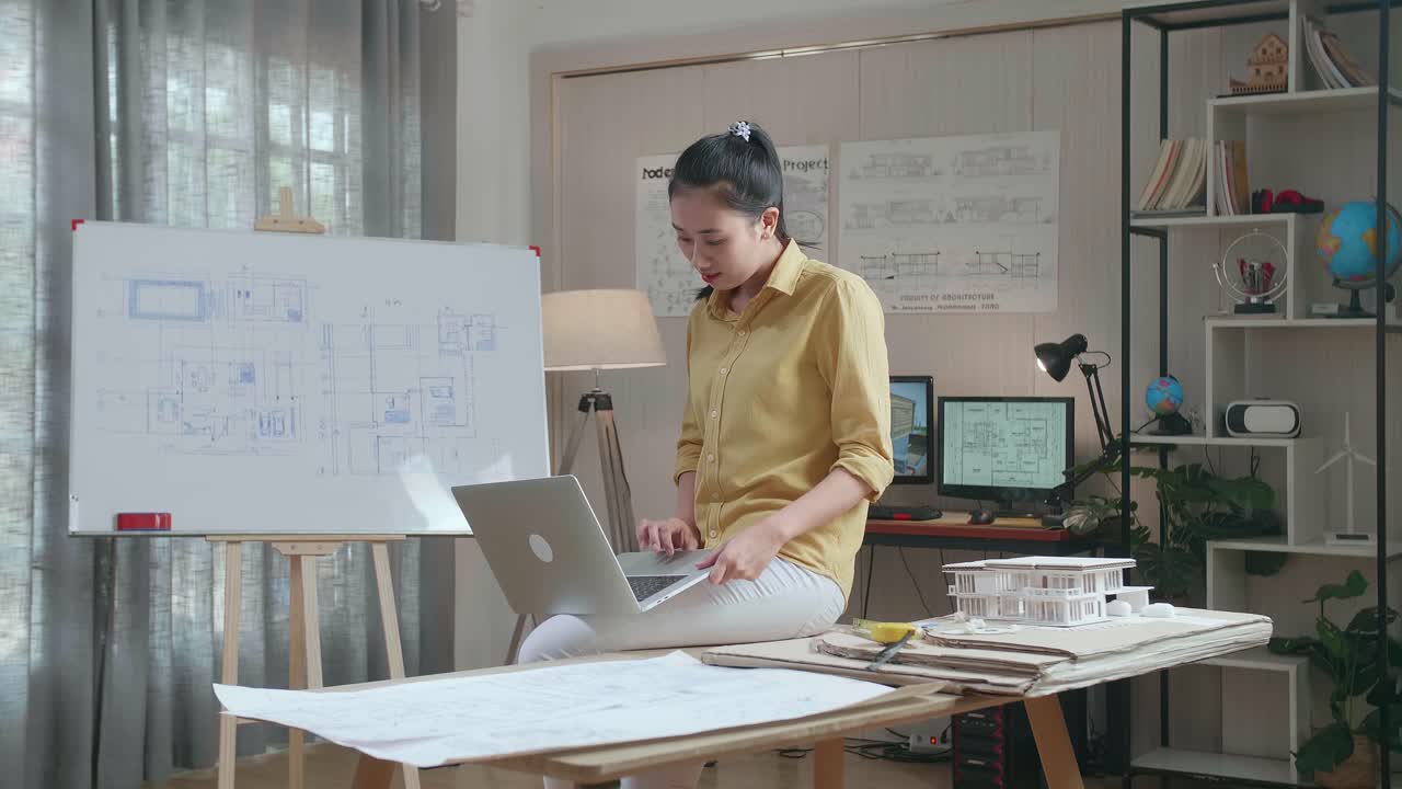 Asian Woman Engineer Sitting On The Table And Using A Laptop To Work At The Office