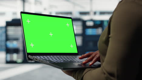 technician with green screen laptop in data center