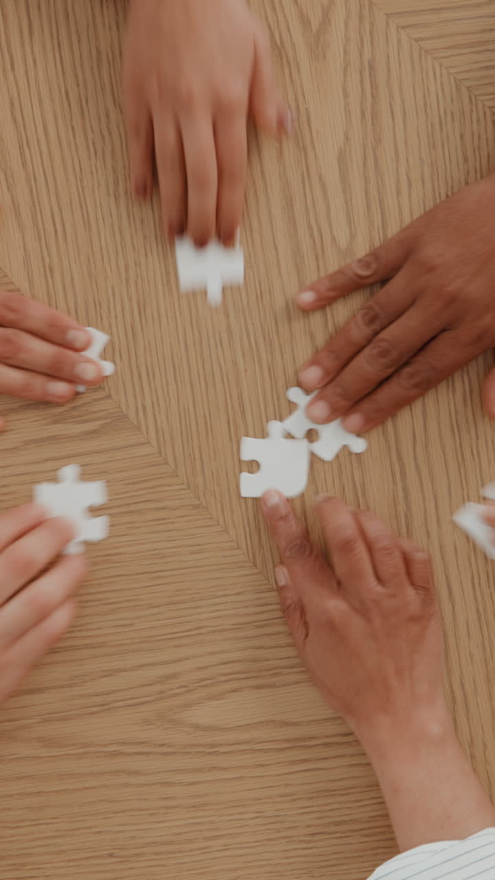 Mani che assemblano pezzi di puzzle bianchi su un tavolo di legno
