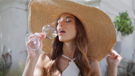 vacation girl drinking wine glass at sunny cafe closeup. straw hat woman rest