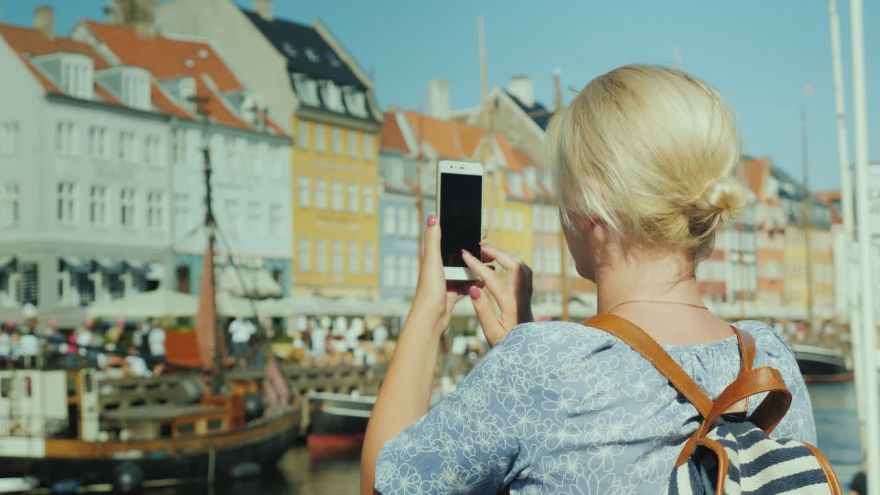 관광객들은 덴마크 코펜하겐의 아름다운 운하와 유명한 관광 거리를 사진으로 찍습니다.