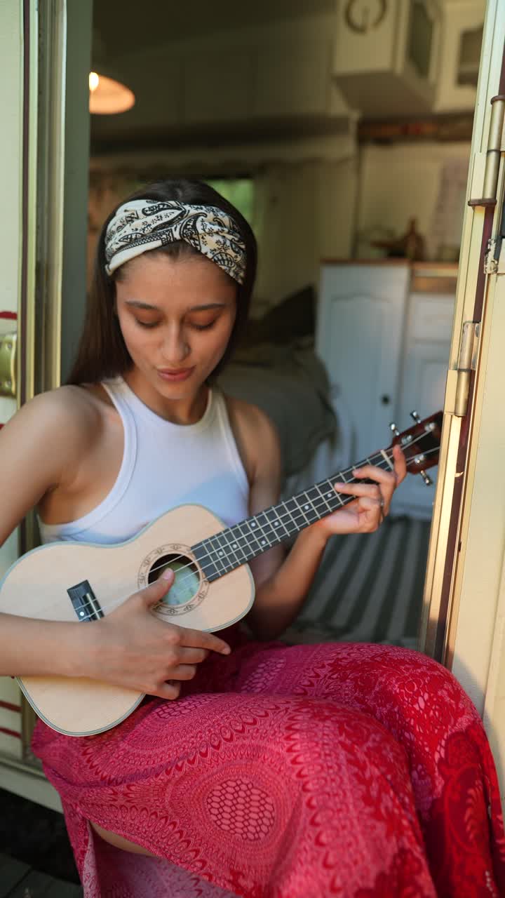 mujer tocando el ukulele en una caravana