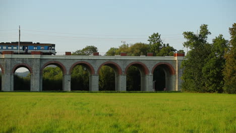 Slow-motion-railway-viaduct-with-a-passing-passenger-train-crossing-the-bridge