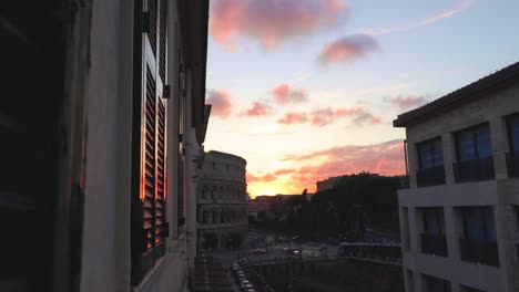 very rare unique view of the famous colosseum of rome from a window above! during sunset, the clouds turn red.