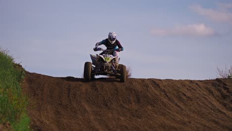 quad bike race driver jumps over a hill during the race