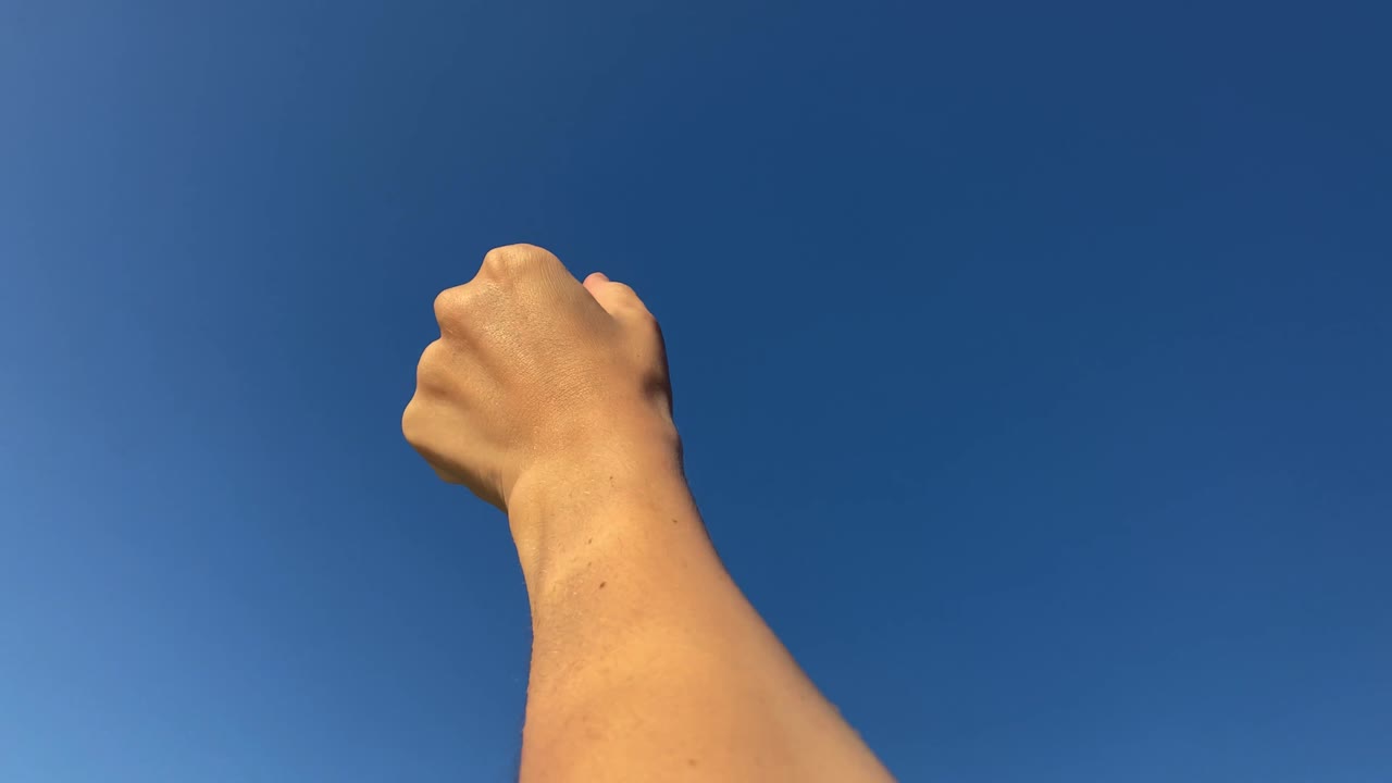 손을 들고, 하늘에 손을 올리고, 깊고 푸른 하늘에 손이 두드러지고, 피부에 물이 반사되는 것을 볼 수 있습니다.