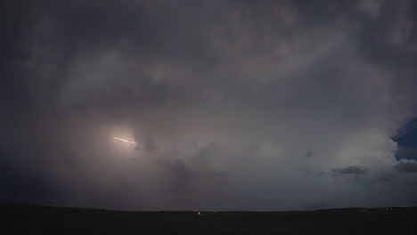 bolt of lightning quickly flickers through dark storm clouds in soft dusk light