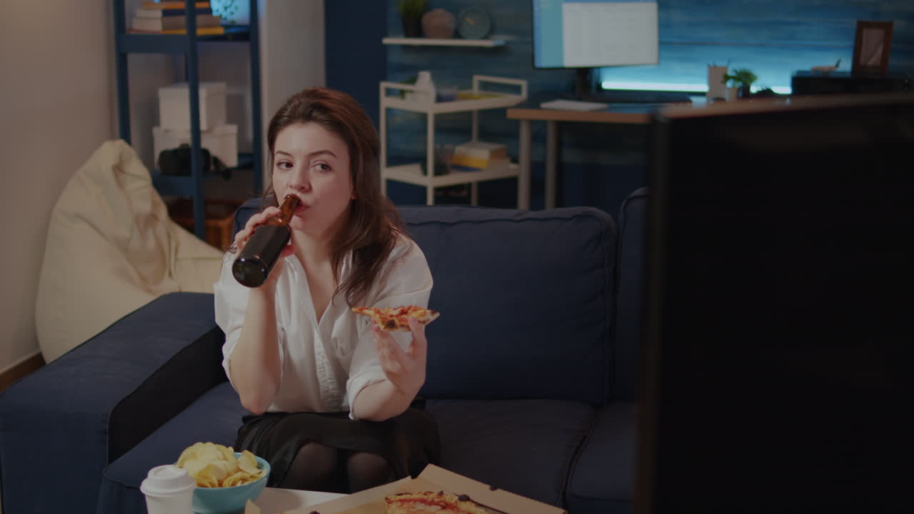 Young adult drinking beer from bottle in living room