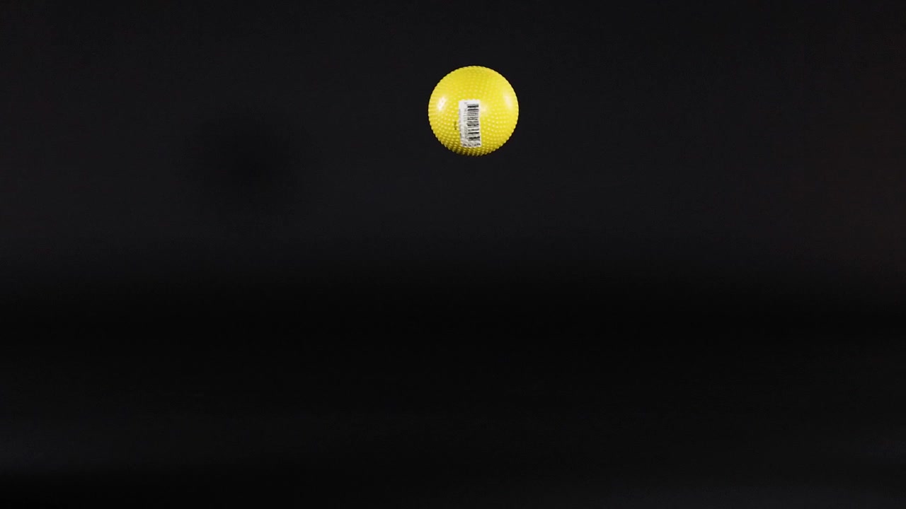A yellow ball bounces against a dark background