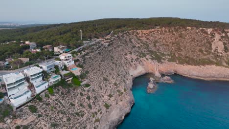 Aerial---coastal-villa-buildings-on-rugged-limestone-cliff,-Mallorca