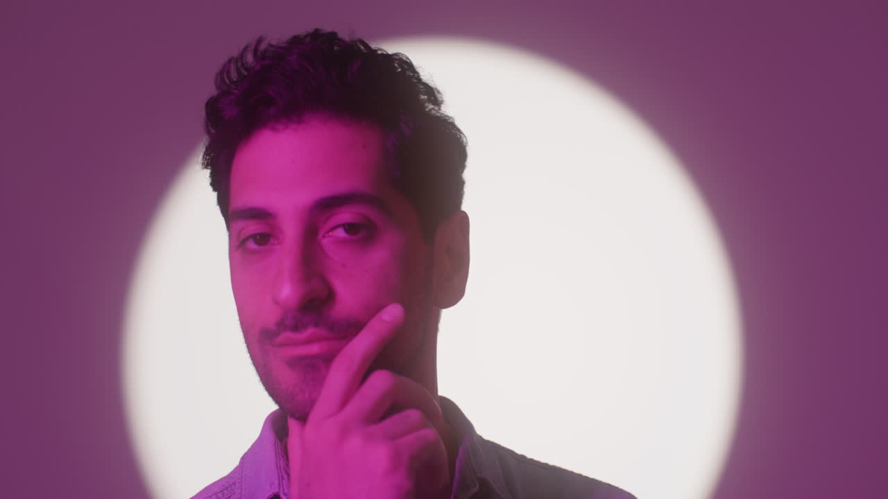 un hombre atractivo mira a la cámara mientras se toca la cara