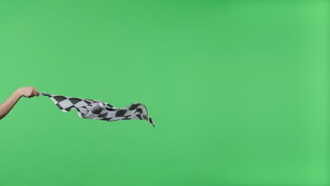 female hand holding and waving checkered race flag in slow motion against green screen background. victory, achievement, success, sport concept. silk black and white checkered flag finish start race