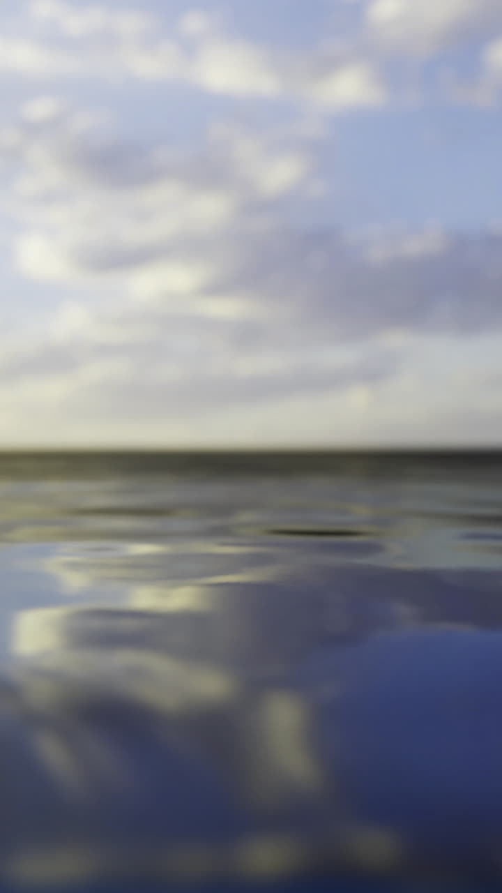 Rippling water reflects clouds above on a sunny day at the ocean