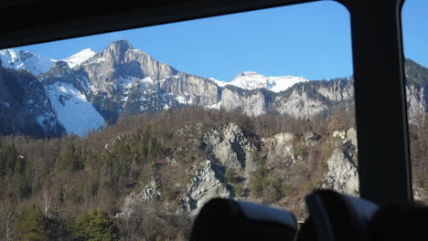 window seat view showing snow capped mountains on glacier express train in switzerland