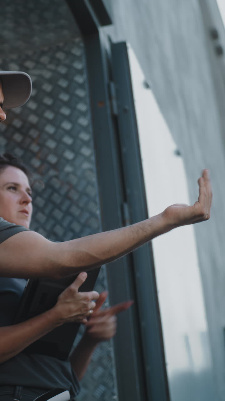 Two logistics or warehouse workers, a man and a woman, discussing and planning with a tablet and gloves
