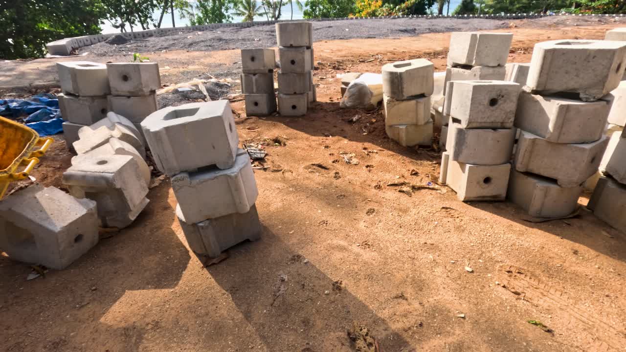 푸켓 해변 근처의 모래 땅 위에 쌓여있는 석회 블록, 밝은 낮에 그림자와 바다를 배경으로 찍은 사진