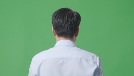 back view close up of asian business man walking on green screen background in the studio