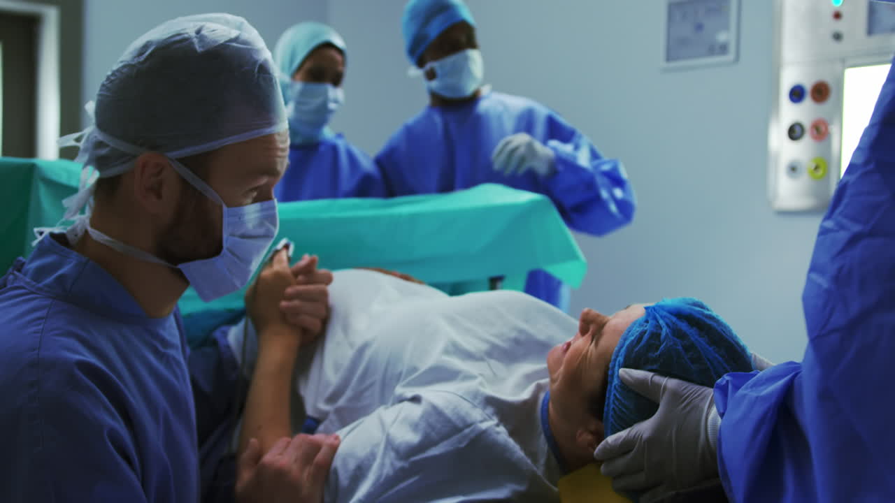 Vista lateral de homem caucasiano confortando mulher durante as dores do parto na sala de cirurgia do hospital 4k