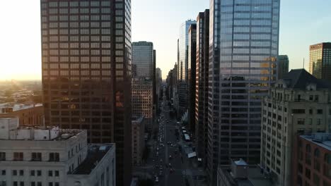 cityscape at sunset showcases tall glass structures and busy streets filled with cars. golden light reflects off buildings as the sun sets, creating a vibrant urban scene.