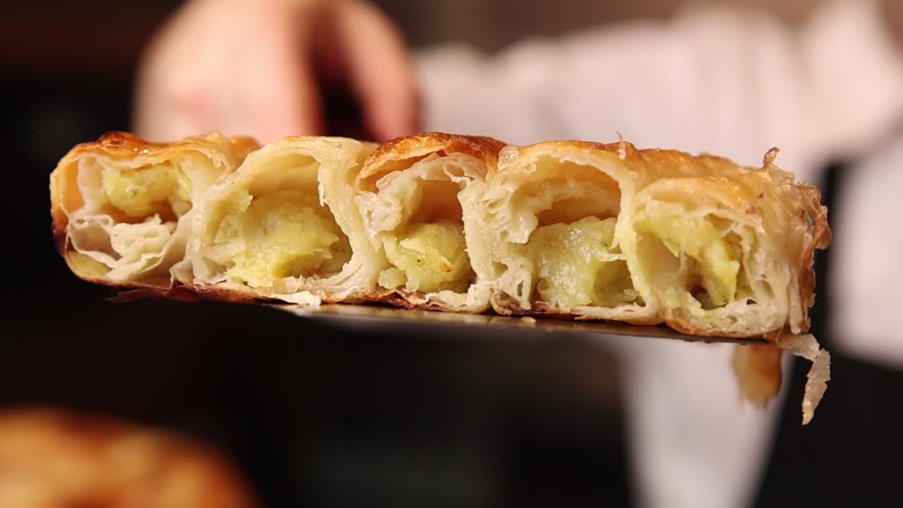 Primo piano di un rustico salato con ripieno di patate su una spatola.