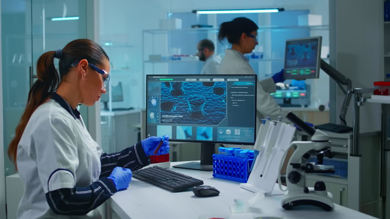 Chemist doctor holding test tube with blood sample entering datas in pc
