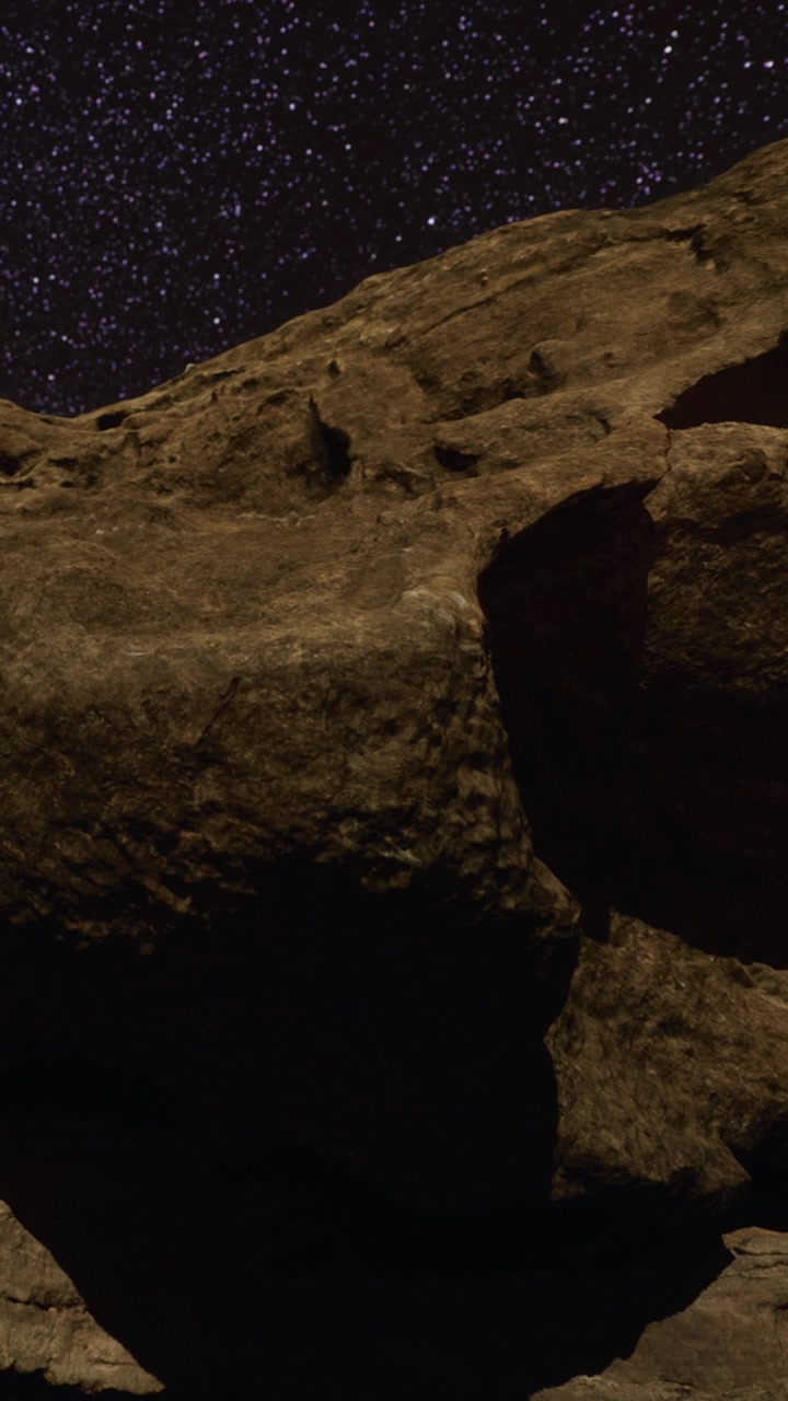 Vista di una formazione rocciosa sotto un cielo notturno costellato di stelle e spazio.