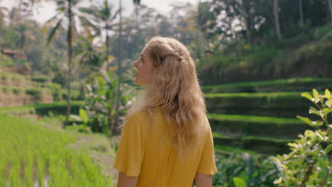 beautiful woman in rice paddy wearing yellow dress enjoying vacation exploring looking at rice terrace farm sightseeing travel through bali indonesia 4k