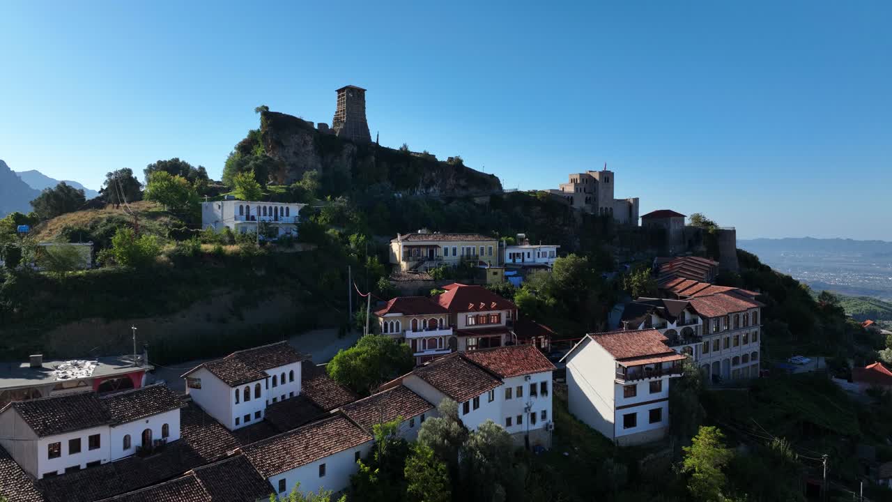 Drone reveals Kruja castle and rooftops in Albania with surrounding forest and sunny weather, ascend
