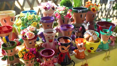 colorful decorative flower pots with playful faces on display at a market table