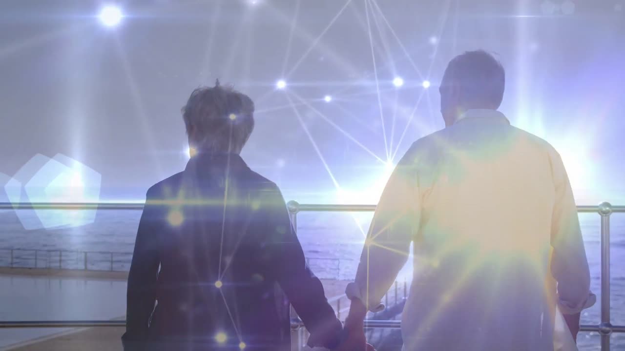 縦型動画：手をつないで歩く高齢者が、バッグを手に手すり越しに海を眺めています。オーバーレイが明るくなります。