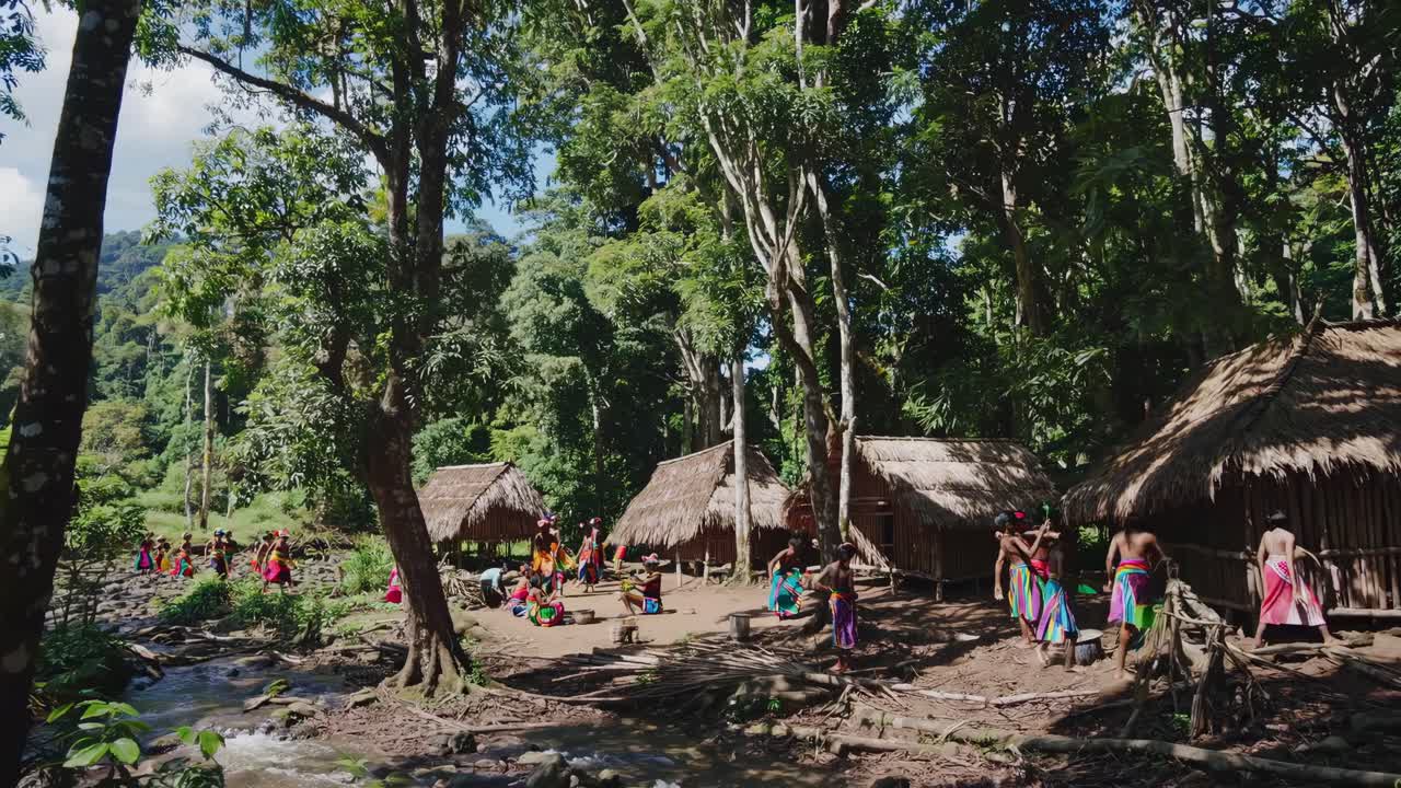Aerial video captures a vibrant tribal village nestled in lush forest, showcasing traditional huts