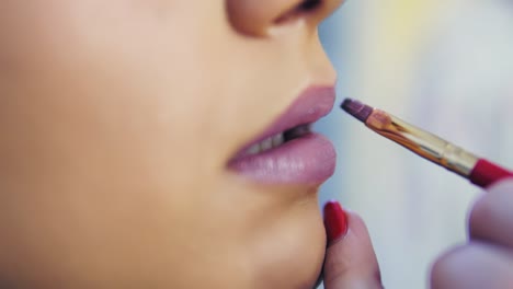 closeup view of a professional makeup artist applying lipstick on model's lips working in beauty fashion industry