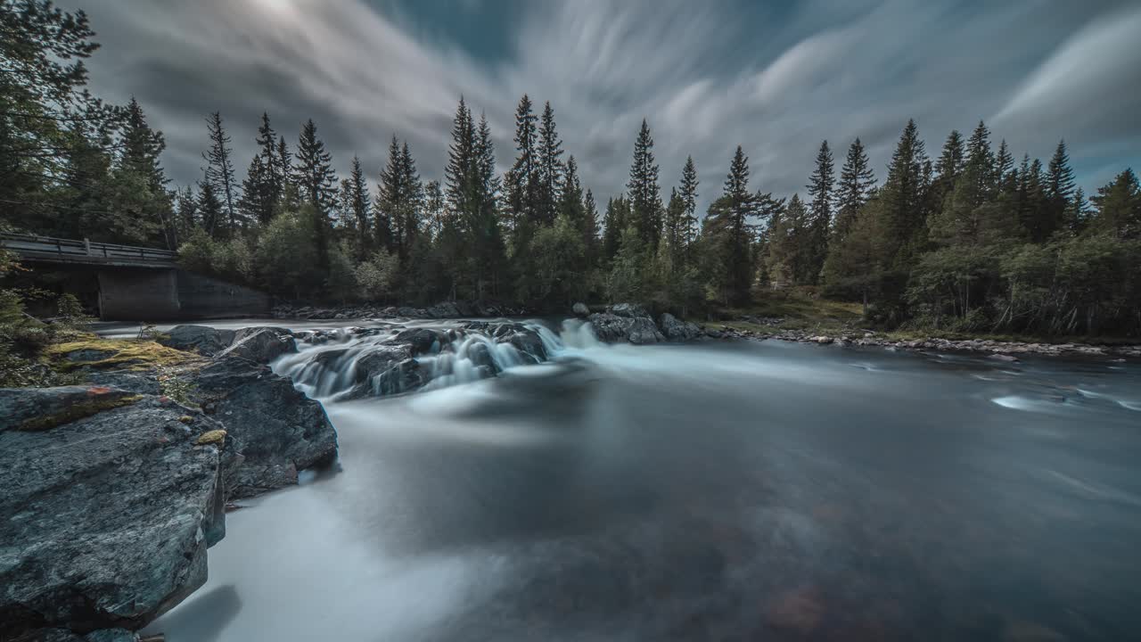 A long exposure video of the shallow mountain river with a small waterfall