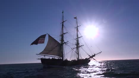 a tall masted clipper ship sails on the high seas with an american flag flying 2